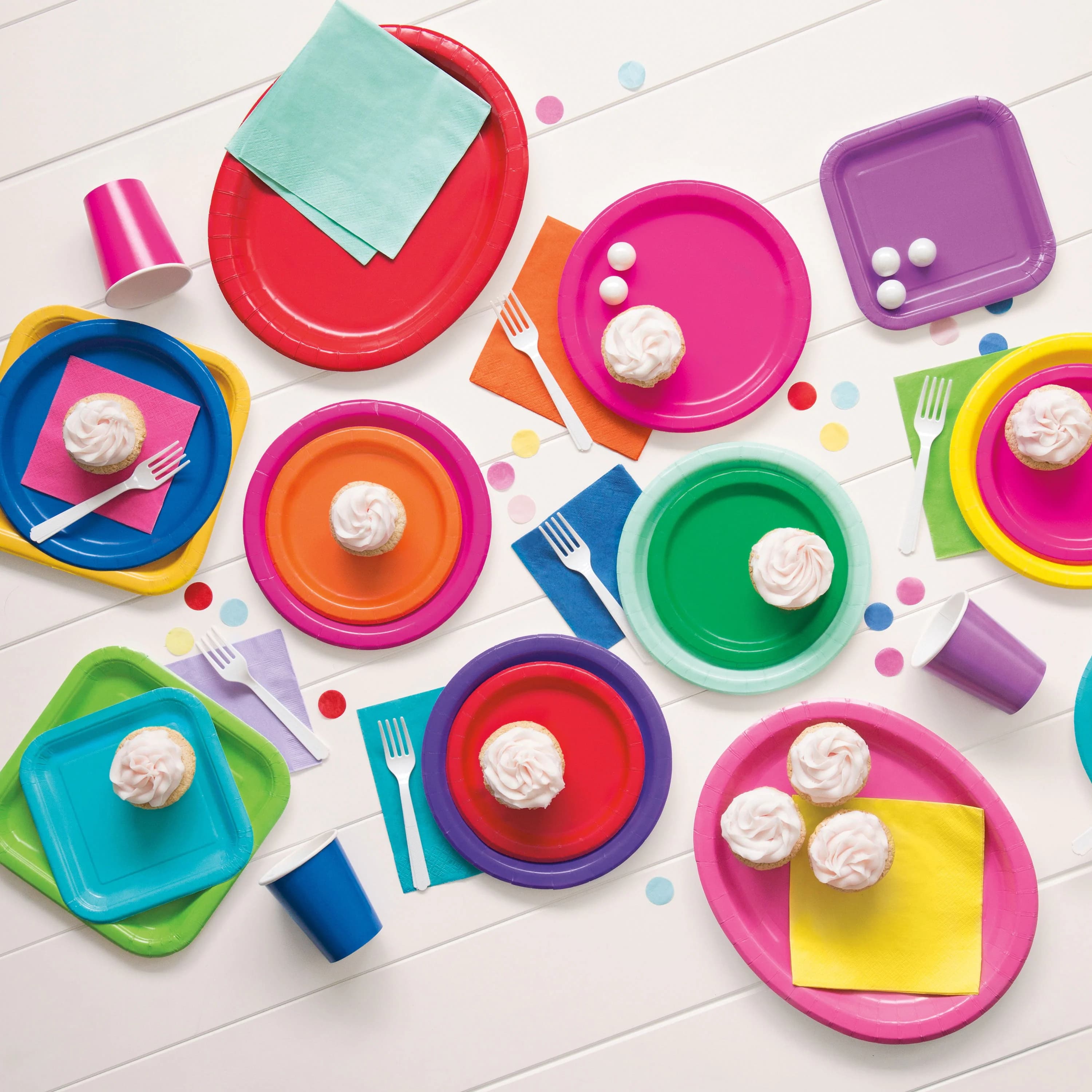Colorful party plates, napkins, cups, and cupcakes arranged for a celebration